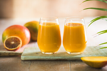 Two mango lassi or kesar milk in glasses. Indian healthy ayurvedic cold drink with mango. Freshness lassi made of yogurt, water, spices, fruits and ice.
