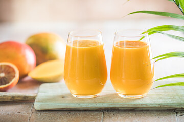 Two mango lassi or kesar milk in glasses. Indian healthy ayurvedic cold drink with mango. Freshness...
