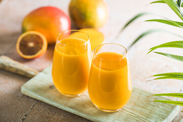 Two mango lassi or kesar milk in glasses. Indian healthy ayurvedic cold drink with mango. Freshness lassi made of yogurt, water, spices, fruits and ice.