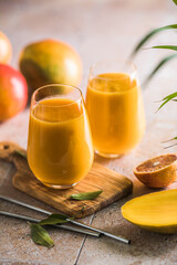 Two mango lassi or kesar milk in glasses. Indian healthy ayurvedic cold drink with mango. Freshness lassi made of yogurt, water, spices, fruits and ice.