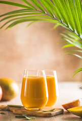 Two mango lassi or kesar milk in glasses. Indian healthy ayurvedic cold drink with mango. Freshness lassi made of yogurt, water, spices, fruits and ice.