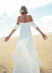 Fototapeta na wymiar Photo of a woman in amazing white wedding dress posing on the desert,