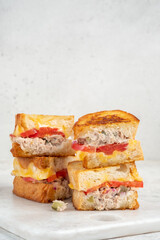 A closeup view of a tuna melt sandwich with cheese and tomato