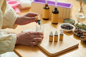 Hands of woman adding colorant into soap base
