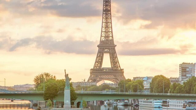 Eiffel Tower sunrise timelapse with boats on Seine river and in Paris, France. View from Mirabeau bridge. Modern buildings and The Statue of Liberty. Dramatic sky