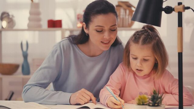 Mother assisting daughter with early education and development through homework