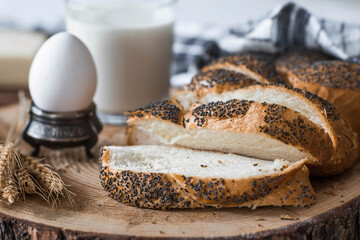 Classic wheat braid with poppy seeds. Delicious bread close-up. Freshly baked sourdough bread with a golden crust on a wooden board. The context of a bakery with delicious bread. 