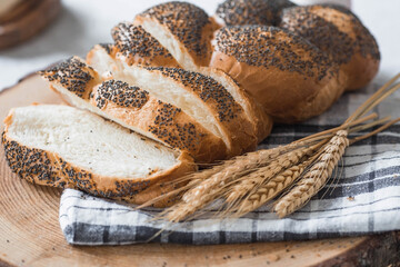 Classic wheat braid with poppy seeds. Delicious bread close-up. Freshly baked sourdough bread with a golden crust on a wooden board. The context of a bakery with delicious bread. 