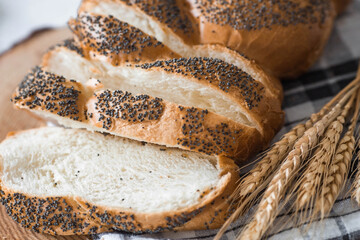 Classic wheat braid with poppy seeds. Delicious bread close-up. Freshly baked sourdough bread with a golden crust on a wooden board. The context of a bakery with delicious bread. 