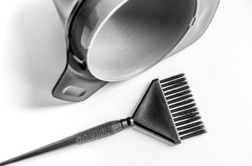 A black plastic brush for hair coloring lies near the empty mixing bowls. Black and white photo. Horizontal