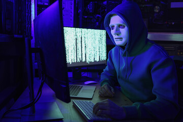 Hacker in mask working with computers in dark room. Cyber attack