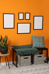 Empty frames hanging on orange wall in stylish room. Mockup for design