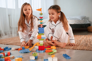 Toy building by construction toys. Two little girls are playing and having fun together in domestic room