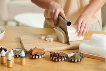 Hands of woman using special knife for cutting soap base into thin slices