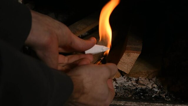 un'uomo prepara il fuoco nella stufa, la legna che arde in una casa di montagna