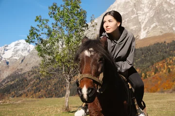 Foto op Canvas Young woman riding horse in mountains on sunny day. Beautiful pet © New Africa
