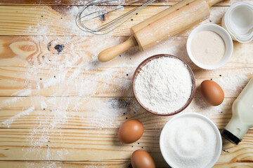 Homemade dough recipe (eggs, flour, milk, sugar) and kneaded dough on a wooden table. view from...