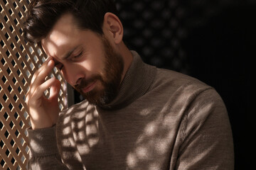 Upset man listening to priest during confession in booth