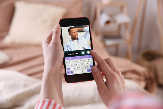 Woman viewing male profile on dating site via mobile phone at home, closeup