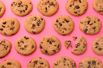 Many delicious chocolate chip cookies on pink background, flat lay