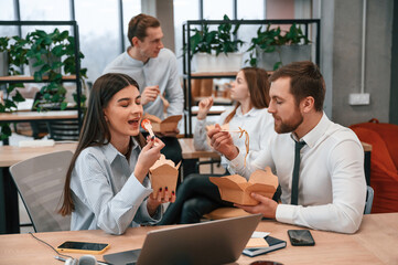 Having a conversation. Group of coworkers are eating food from eco boxes in the office together