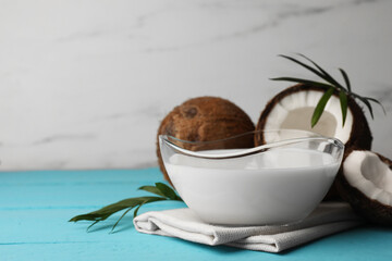 Bowl of delicious vegan milk, palm leaves and coconuts on light blue wooden table. Space for text