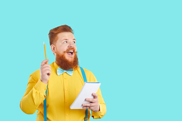 Funny cheerful bearded man in yellow shirt and blue bow tie standing on blank copyspace background,...