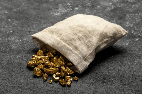 Overturned Sack Of Gold Nuggets On Grey Table