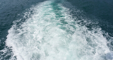 Fototapeta na wymiar White splash foams behind a ship engine on the sea. Foam bubbles on sea water surface. 