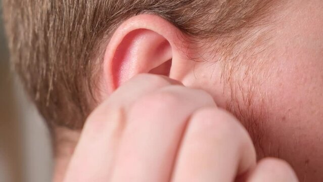 A man inserts earplugs in his ears so as not to hear extraneous noise, music, snoring. Silicone earplugs for sleeping.