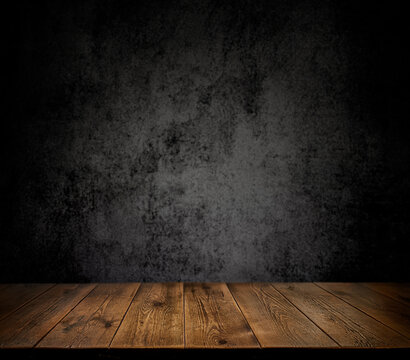  An empty wooden countertop against a black, dark concrete wall. Home interior. Evening, dim light. Space for text. Copy space