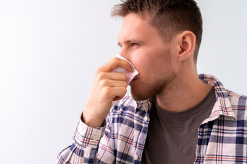 young male blowing nose in the napkin, feeling sick, health problems
