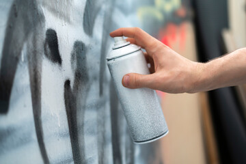 hand holding spray paint can, artist doing graffiti art on the wall