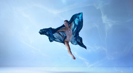 Shot of jumping ballerina with stretched feet over blue background. Beauty of contemporary dance © Lustre Art Group 