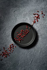 Ziarna czerwonego pieprzu na talerzyku na ciemnym tle Czerwony pieprz Red peppercorns on a plate on a dark background - obrazy, fototapety, plakaty