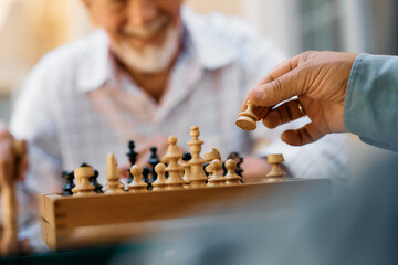 Close up of senior men playing chess outdoors.