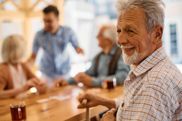 Happy senior man relaxes with group of friends on terrace at residential care home.