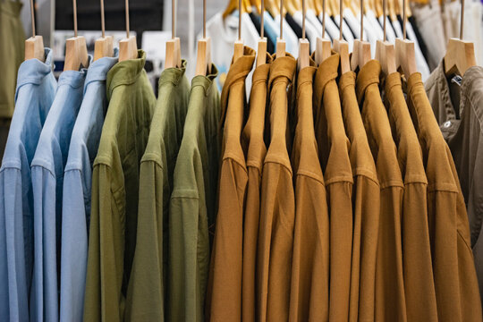 Shirts of neutral tones on hanger in clothing