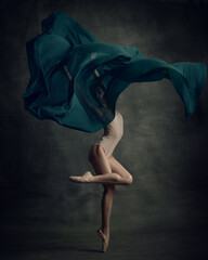 Shot of professional ballerina dancing in beige bodysuit with fabric isolated over dark green...