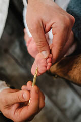 Baptism ceremony of a baby. Close up of tiny baby feet, the sacrament of baptism. The godfather...