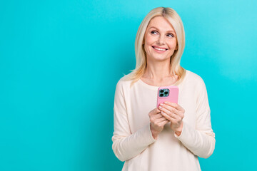 Photo of pensioner business lady influencer hold new samsung galaxy phone look dreamy empty space ecommerce ad isolated on cyan color background