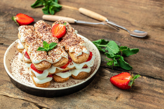 Tiramisu. Homemade tiramisu with fresh strawberry, mascarpone and mint in glass on dark background. Vegan lactose free dessert, Recipe of healthy organic decert