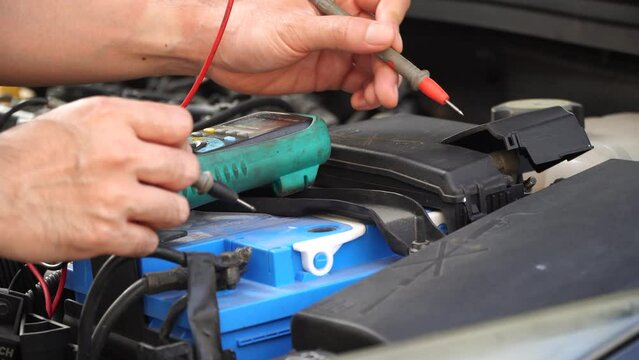technician checks the battery using a voltmeter capacity tester,auto mechanic uses a multimeter voltmeter to check the voltage level in a car battery