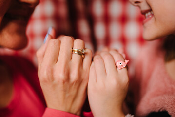 Hands of mother and daughter with rings. Mom hold hands of kid girl, giving supporting at home. Sincere different generations family sharing secrets. Tender moment together, show love. Closeup hands.