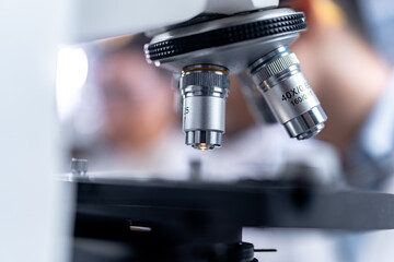 Scientist analyzing microscope slide at laboratory. Young woman technician is examining a histological sample, a biopsy in the laboratory of cancer research