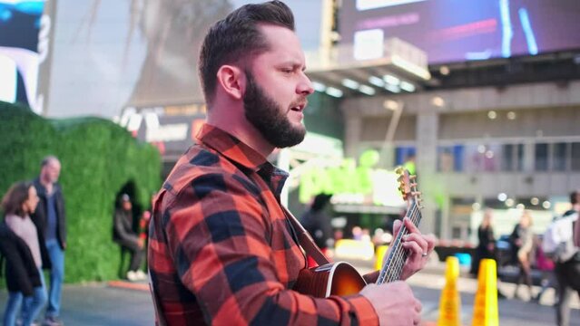 musician is singing in the middle of Times Square and playing a guitar.