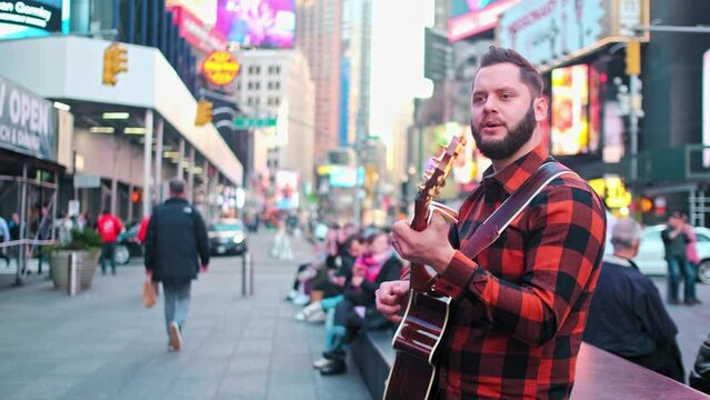 Musician is singing and playing on his guitar in New york city.