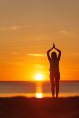 Fototapeta na wymiar yoga meditation, silhouette of woman at sunset in pose tree with outstretched arms. health recreation and outdoor sports. poster, postcard. person is engaged in breathing practices. mental health