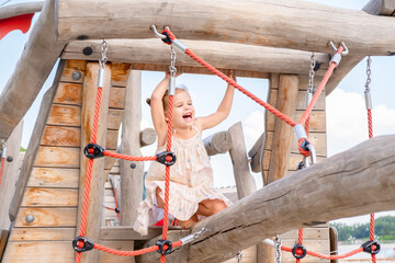 cute little child girl in dress playing on kids playground in summer day