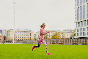 Outdoor training. A young woman runs around the stadium. Healthy lifestyle